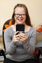 Smiley girl with down syndrome holding phone
