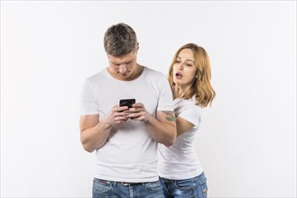 Young woman spying her boyfriend s phone against white background