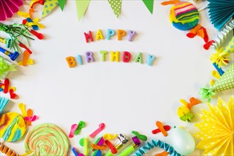 Elevated view happy birthday text with party accessories white surface
