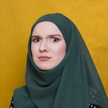 Portrait confused woman looking camera against yellow backdrop