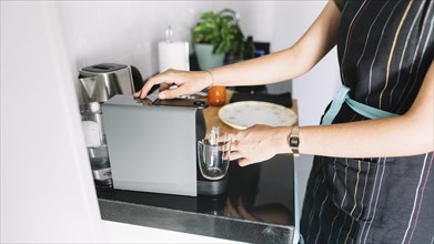 Woman holding glass mug coffee machine kitchen