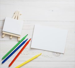 Blank mini easel white paper colors felt tip pen wooden texture backdrop