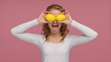 Portrait playful woman holding lemons laughs