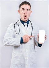 Shocked doctor pointing an application on the cell phone. Amazed young doctor holding and pointing cell phone screen
