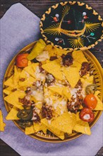 Garnished tasty mexican nachos plate with mexican hat table