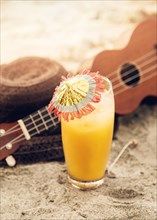 Glass with drink ukulele straw hat placed sand