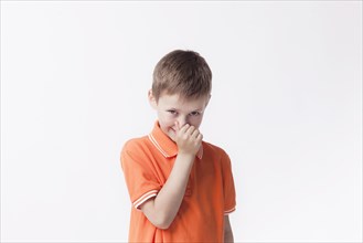 Boy closing his nose with fingers looking camera white background