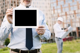 Close up old man holding up tablet
