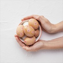 Top view bowl with decorated easter eggs hands