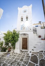 White Greek Orthodox church with bell tower and sun star