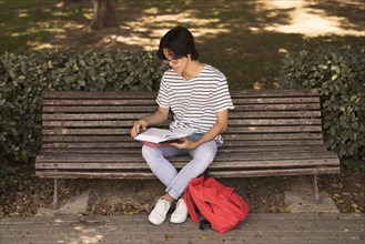 Asian teen man with textbook bench
