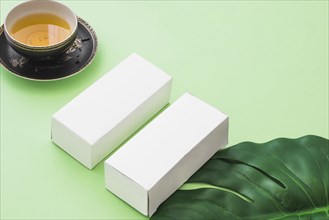 Herbal tea cup two white boxes with leaf green background