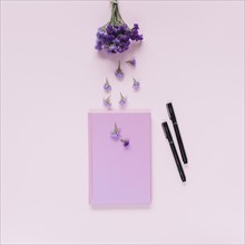 Lavender closed notebook two felt tip pens pink background