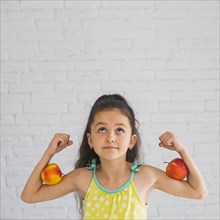 Girl flexing her hands holding apple her biceps looking up