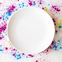 Holi color powder around white blank empty plate