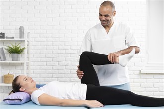 Male physiotherapist checking woman s leg flexibility