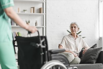 Nurse holding wheelchair front senior female patient