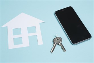 Paper cutout house keys with cellphone blue background