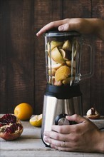 Blender with various fruit wooden background