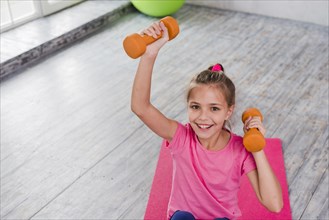 Portrait smiling girl exercising with orange dumbbell