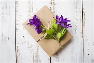 Top view purple flowers tied with gift box white wooden backdrop