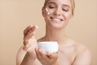 Blonde woman with face cream jar