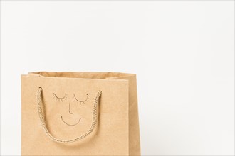 Human face drawn brown paper bag against white surface