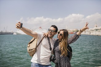 Woman making peace sign with her boyfriend taking selfie mobile