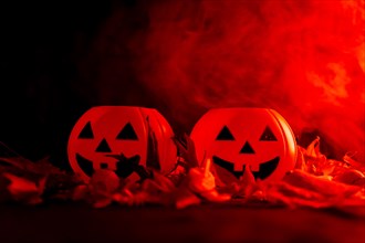 Detail of Halloween pumpkins on autumn leaves with smoke on a red background