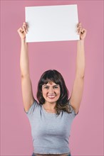 Smiling woman raising up a blank sign against a pink background