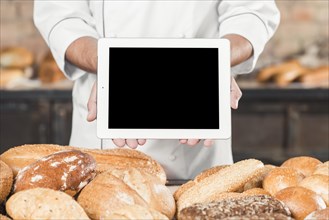 Close up male baker showing blank digital tablet baked bread