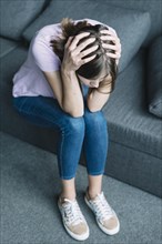 Young woman suffering from headache sitting sofa