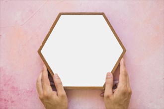 Close up person placing white hexagon frame pink wall