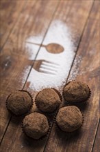 Homemade chocolate truffle candies with cocoa powder near spoon fork shape sugar powder