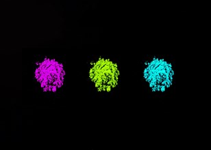 Pink green turquoise holi colors arranged row black background