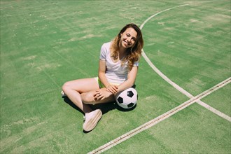 Happy teenager with ball football pitch