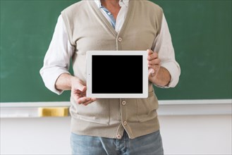 Professor holding tablet with blank space classroom
