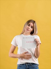 Female puts hand abdomen showing period calendar