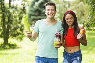 Young couple with healthy food standing garden