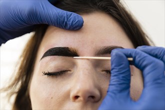 Woman getting eyebrow treatment from beautician