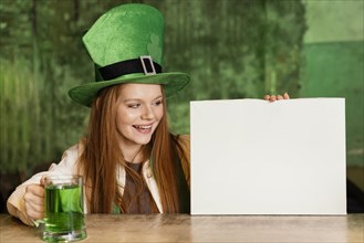 Smiley woman celebrating st patrick s day bar with blank placard drink