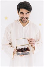 Eid al fitr concept with muslim man holding box dates