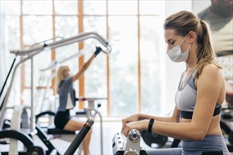 Woman gym using equipment with medical mask