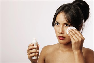 Young woman with cosmetic lotion cotton pad