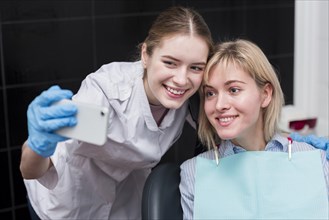 Happy dentist taking selfie with patient