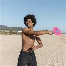 Black man with tennis racket beach