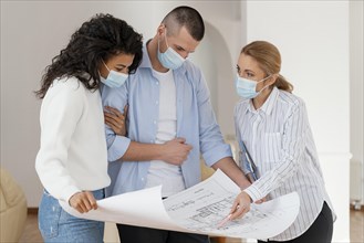 Realtor couple with medical masks looking house plans