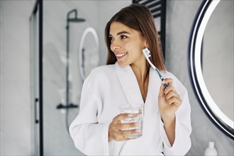 Young woman holding toothbrush glass water