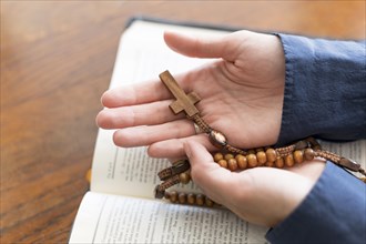 High angle person holding rosary with holy book open