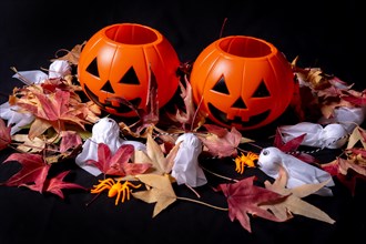 Detail of Halloween pumpkins over red autumn leaves and ghosts on a black background